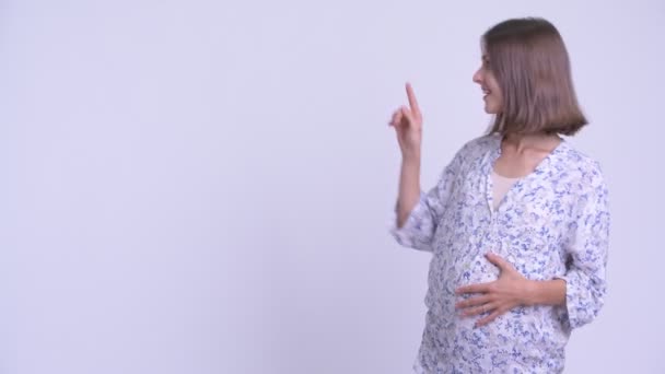 Happy young pregnant woman touching something and crossing arms — Stock Video