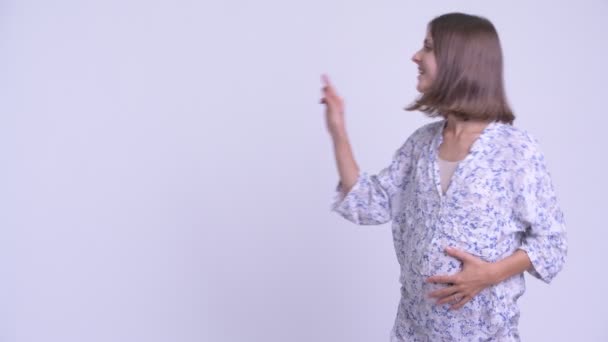Счастливая молодая беременная женщина трогает что-то и выглядит удивленной — стоковое видео