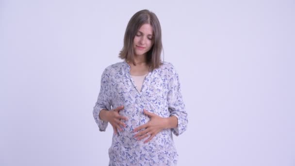 Серьезная молодая беременная женщина думает и смотрит вниз — стоковое видео