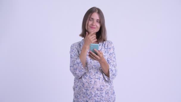 愉快的年轻孕妇思考, 同时使用手机 — 图库视频影像