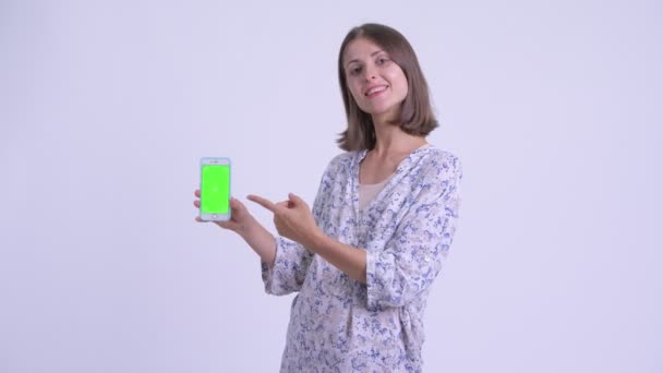 Szczęśliwa młoda kobieta w ciąży mówi i pokazuje telefon — Wideo stockowe