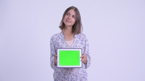 Szczęśliwy młoda kobieta w ciąży myślenia podczas pokazywania cyfrowego tabletu — Wideo stockowe