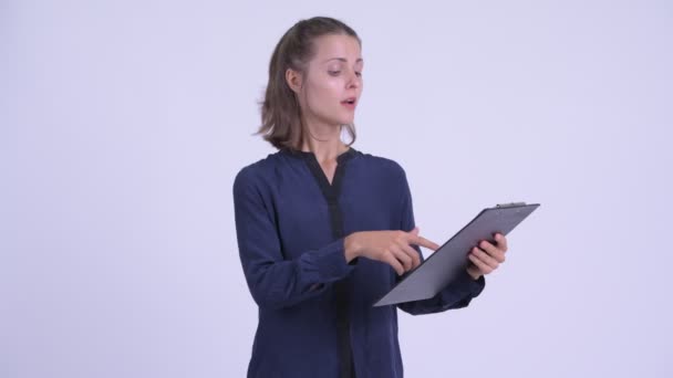 Happy young beautiful businesswoman talking while reading on clipboard — Stock Video