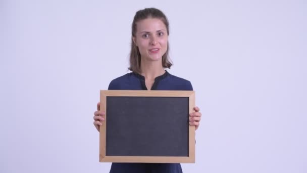 Happy young beautiful businesswoman talking while holding blackboard — Stock Video