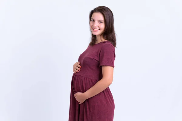 Профиль счастливой молодой красивой беременной женщины, смотрящей в камеру — стоковое фото