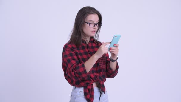 Jonge mooie hipster vrouw met behulp van telefoon en op zoek geschokt — Stockvideo