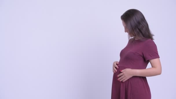 Профиль счастливой молодой красивой беременной женщины, указывающей пальцем — стоковое видео