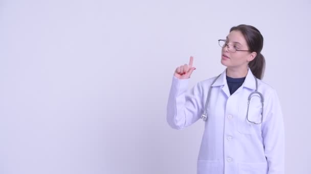 Счастливая молодая красивая женщина врач думает и указывает вверх — стоковое видео
