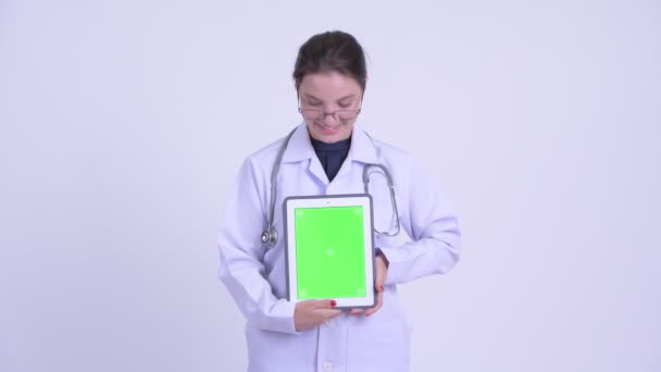 Щаслива молода красива жінка лікар думає, показуючи цифровий планшет — стокове відео