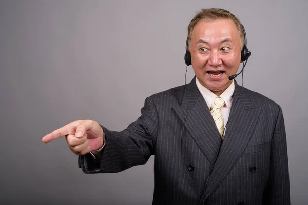 Porträtt av mogen asiatisk affärsman mot grå bakgrund — Stockfoto