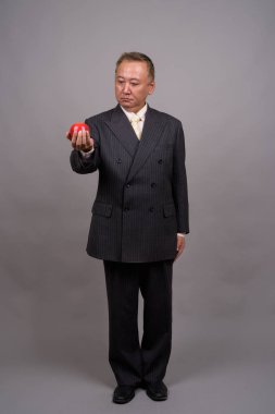 Gri bir arka plana dayanır Olgun Asya işadamı portresi