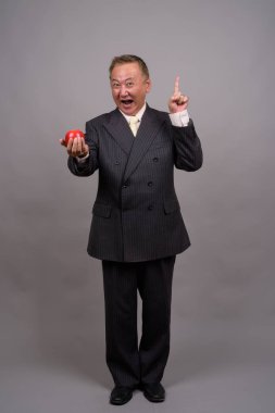 Gri bir arka plana dayanır Olgun Asya işadamı portresi