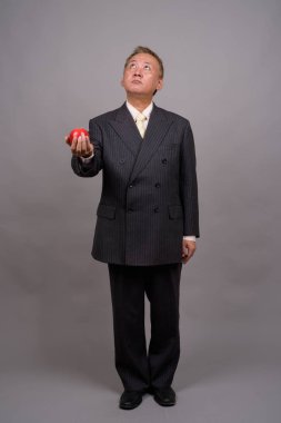 Gri bir arka plana dayanır Olgun Asya işadamı portresi