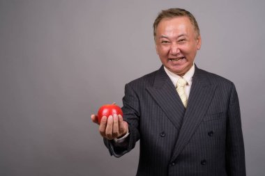 Gri bir arka plana dayanır Olgun Asya işadamı portresi