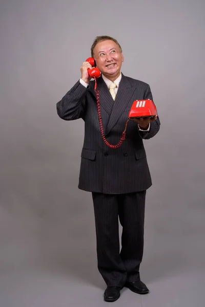 Portret van rijpe Aziatische zakenman tegen de grijze achtergrond — Stockfoto