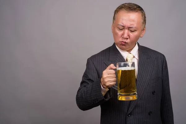 Portrét zralé asijské podnikatel šedém pozadí — Stock fotografie