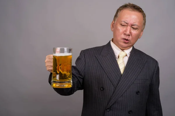 Portrait of mature Asian businessman against gray background — Stock Photo, Image