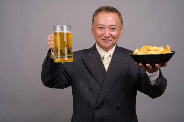 Portret van rijpe Aziatische zakenman tegen de grijze achtergrond — Stockfoto