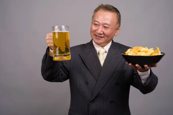 Portrait of mature Asian businessman against gray background — Stock Photo, Image