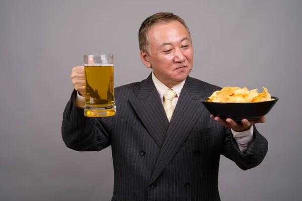 Portrait of mature Asian businessman against gray background — Stock Photo, Image