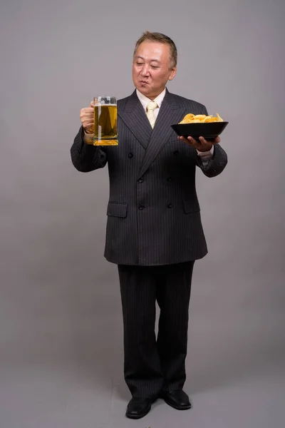 Porträt eines reifen asiatischen Geschäftsmannes vor grauem Hintergrund — Stockfoto