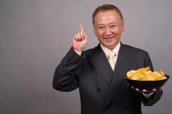 stock image Portrait of mature Asian businessman against gray background