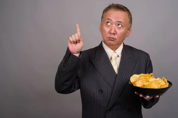 Porträtt av mogen asiatisk affärsman mot grå bakgrund — Stockfoto