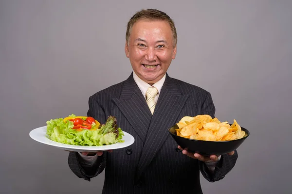 Portret van rijpe Aziatische zakenman tegen de grijze achtergrond — Stockfoto