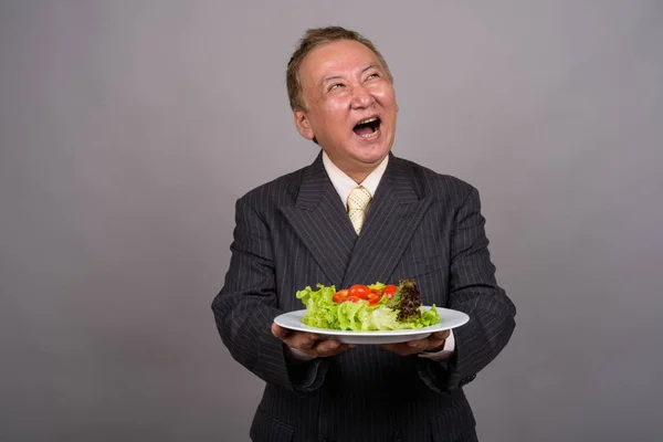 Retrato de homem de negócios asiático maduro contra fundo cinza — Fotografia de Stock