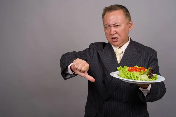 Portret van rijpe Aziatische zakenman tegen de grijze achtergrond — Stockfoto