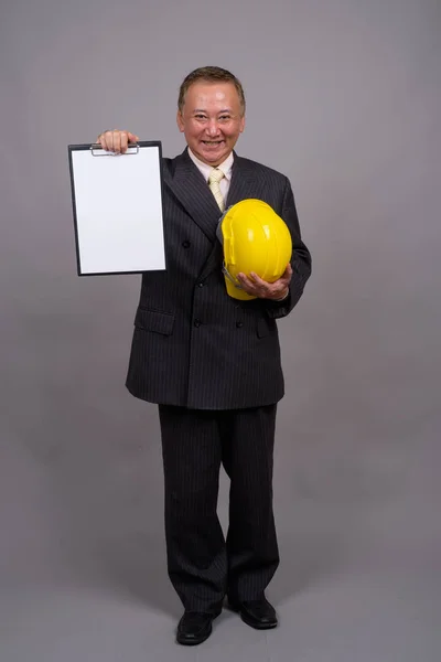 Mature Asian construction businessman against gray background — Stock Photo, Image