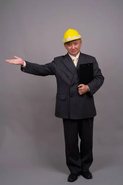Volwassen Aziatische bouw zakenman tegen grijze achtergrond — Stockfoto