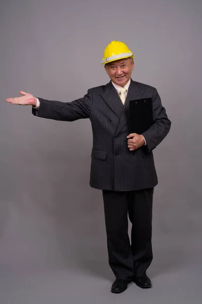 Maturo asiatico costruzione uomo d'affari contro grigio sfondo — Foto Stock