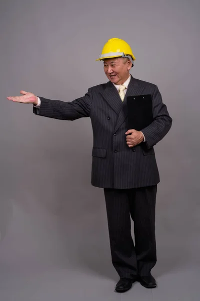 Mature Asian construction businessman against gray background — Stock Photo, Image