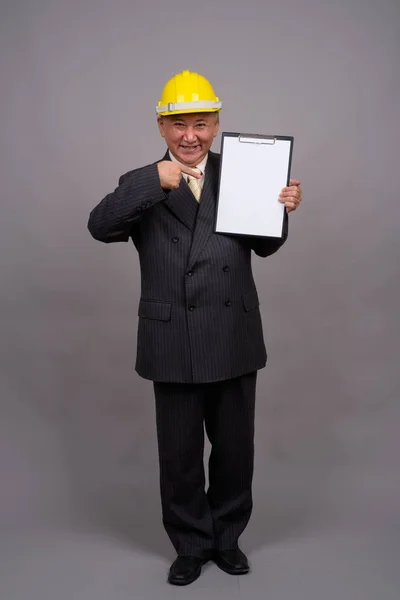 Mature Asian construction businessman against gray background — Stock Photo, Image