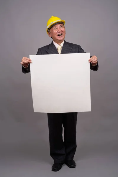 Зрелый азиатский строительный бизнесмен на сером фоне — стоковое фото