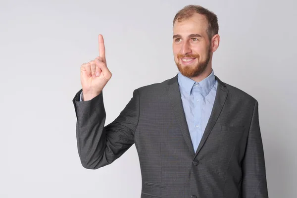 Glücklicher junger bärtiger Geschäftsmann denkt und zeigt nach oben — Stockfoto