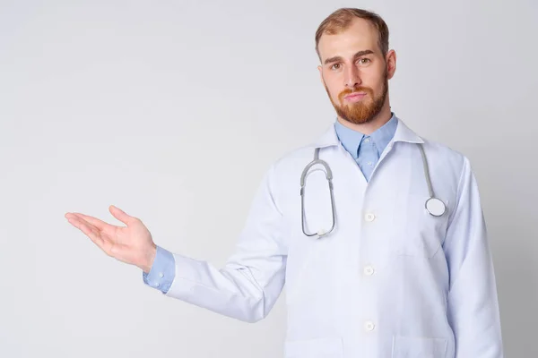 Портрет молодого бородатого чоловіка лікаря, який щось показує — стокове фото