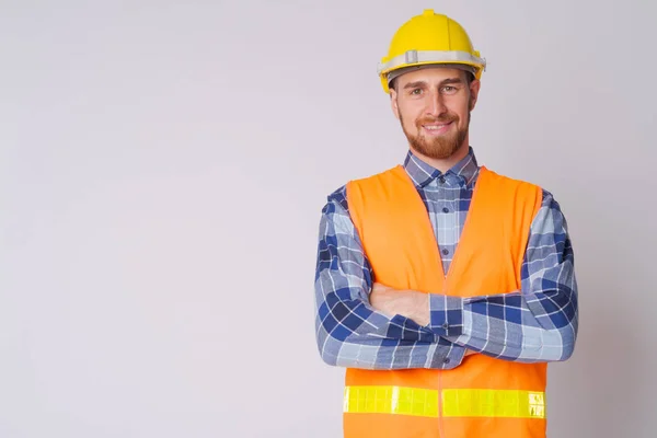 Gelukkige jonge bebaarde man bouwvakker glimlachend met armen gekruist — Stockfoto