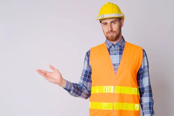 Porträt eines jungen bärtigen Bauarbeiters, der etwas zeigt — Stockfoto