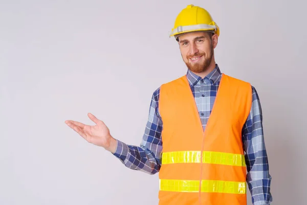 Щасливий молодий бородатий чоловік будівельник показує щось — стокове фото