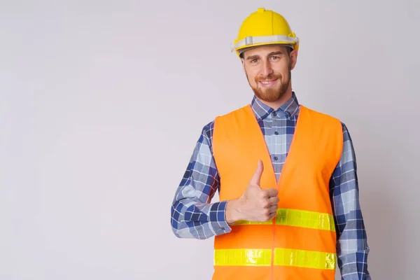 Счастливый молодой бородатый строитель, показывающий большие пальцы — стоковое фото