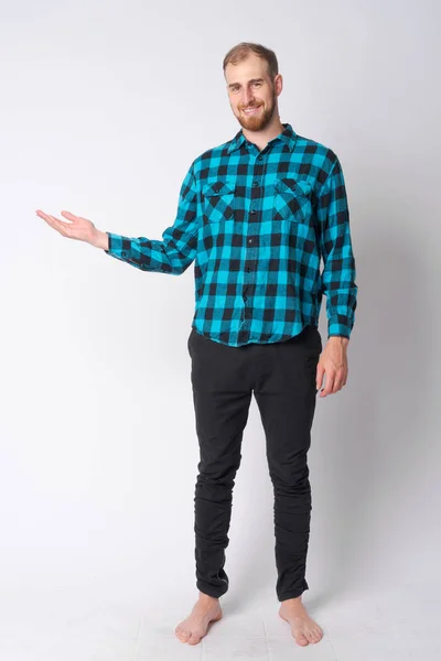 Full body shot of happy young bearded hipster man showing something — Stock Photo, Image