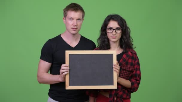 Νεαρό ζευγάρι εκμετάλλευση μαυροπίνακα μαζί — Αρχείο Βίντεο