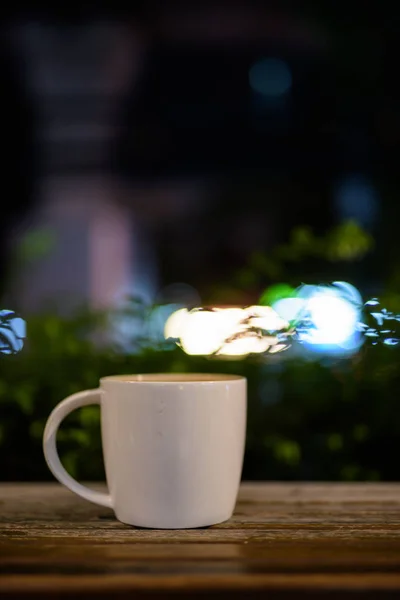 Cangkir kopi pada meja kayu di restoran pada malam hari — Stok Foto
