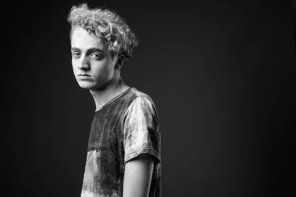 Skinny young man with curly hair against gray background in blac — Stock Photo, Image