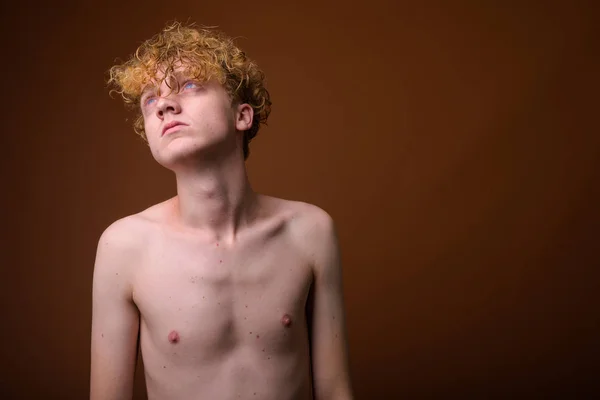 Vékony fiatalember göndör hajú félmeztelen ellen barna backgro — Stock Fotó