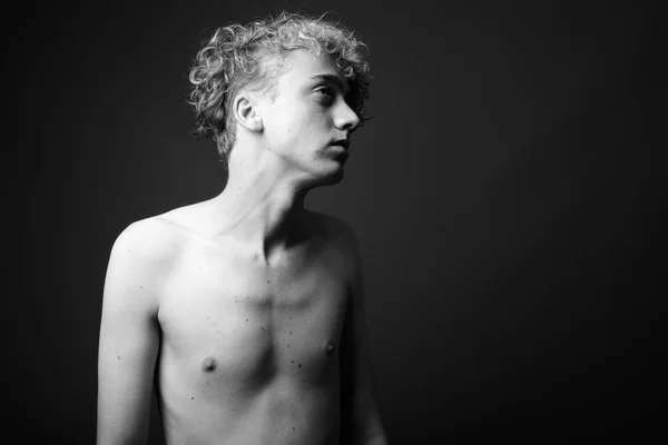 Vékony fiatalember göndör hajú félmeztelen ellen szürke háttérb — Stock Fotó