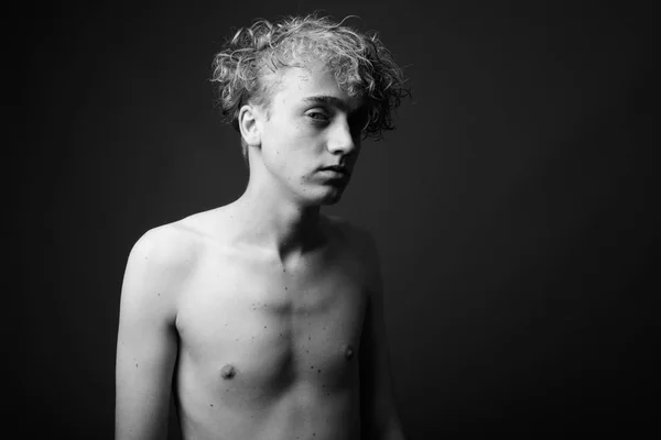 Vékony fiatalember göndör hajú félmeztelen ellen szürke háttérb — Stock Fotó