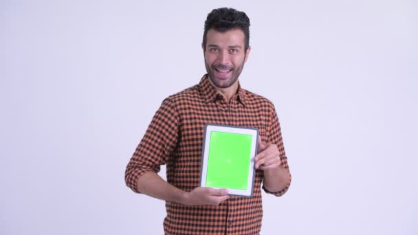 Gelukkig bebaarde Perzische hipster man toont digitale Tablet en op zoek verrast — Stockvideo